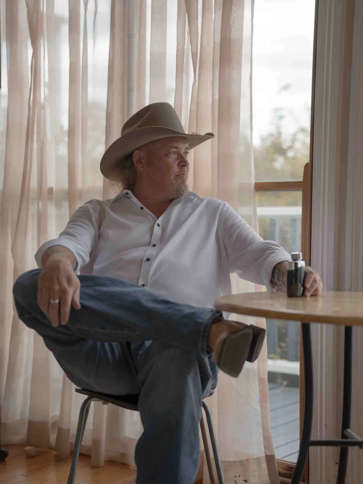 Groom in cowboy hat by window light getting ready – Japanese documentary wedding photographer Sydney